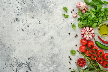 Food cooking background. Fresh saffron, garlic, cilantro, basil, cherry tomatoes, peppers and olive oil, spices herbs and vegetables at light grey slate table. Food ingredients top view.