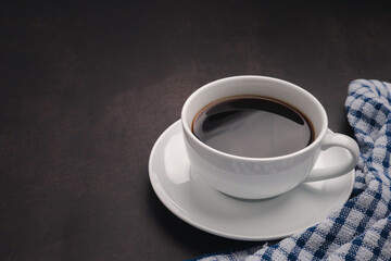 A cup of hot fresh black coffee and cloth on the old kitchen table. Top view with copy space for your text. Concept of the morning, energy, and cheerfulness