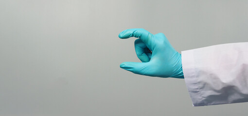 Hand is do holding gesture and wear doctor gown and blue medical glove on grey background.