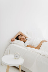 Obraz na płótnie Canvas Sleeping woman in bed with alarm clock.