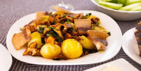 baked potatoes with chanterelles and bacon served with herbs on white plate