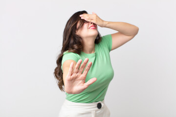 pretty woman covering face with hand and putting other hand up front to stop camera, refusing...