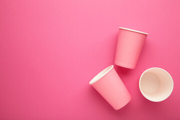 Disposable paper cups on pink background. Top view.