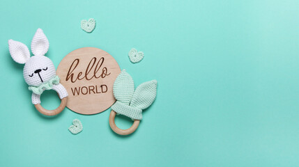 Baby eco wooden toys, beanbag and teethers, wooden tablet Hello World on mint background with copy space.Top view, flat lay.