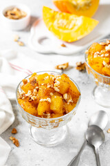 Traditional Turkish dish of baked pumpkin Kabak tatlisi in a glass bowl on a light gray background. Delicious healthy dessert close-up	