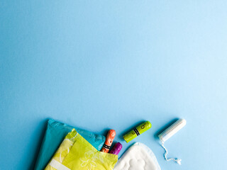 Critical days. Woman hygienic protection, menstruation, cotton tampons, sanitary pads. Feminine hygiene panty liner for menstruation. Menstrual cycle, pad. Blue colorful background. Top view, layout