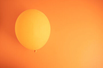 Orange balloon on vibrant orange background with copy space.