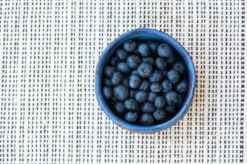 Top view of fresh farm ripe blueberries berries in a blue ceramic vintage cup on a light background. Copy space. Vegetarian breakfast