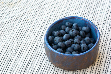 Fresh farm ripe blueberries berries in a blue ceramic handmade cup on a light background. Breakfast mood. Copy space. Vegetarian snack