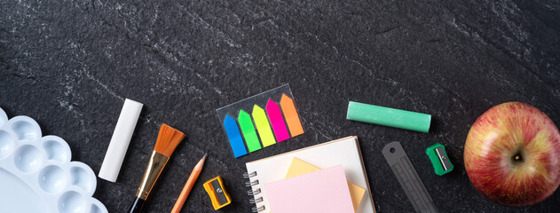 Back to school design concept with stationery over slate black table background.