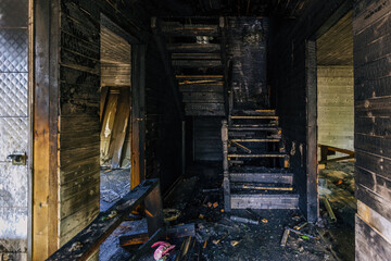 Burnt wooden house interior. Charred stairs and walls. Consequences of fire