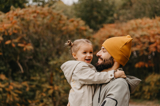 Happy father and daughter playing while walking in a beautiful autumn park. Ideal weekend father with his little daughter. selective focus, noise effect..