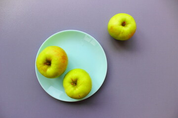 three apples on a plate, grey background