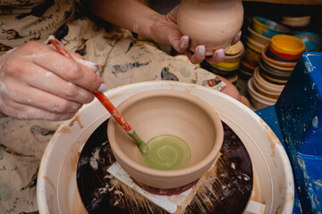 Potter working on potters wheel with clay. Process of making ceramic tableware in pottery workshop. Handicraft and art concept.