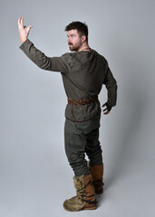 Full length  portrait of  young handsome man  wearing  medieval Celtic adventurer costume.  Standing pose isolated on studio background.