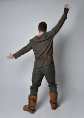 Full length  portrait of  young handsome man  wearing  medieval Celtic adventurer costume.  Standing pose isolated on studio background.