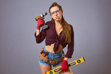 Funny longhaired woman in casual clothes protective gloves hold electric drill or screwdriver in...