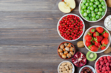 Mix of fresh berries, nuts and fruits. Healthy food contains a lot of vitamins and useful trace elements.Brown wooden background. Copy space.
