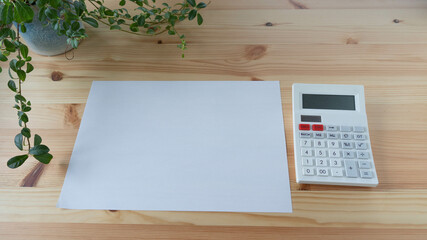 テーブルの上の紙と電卓。空白の紙・横長。