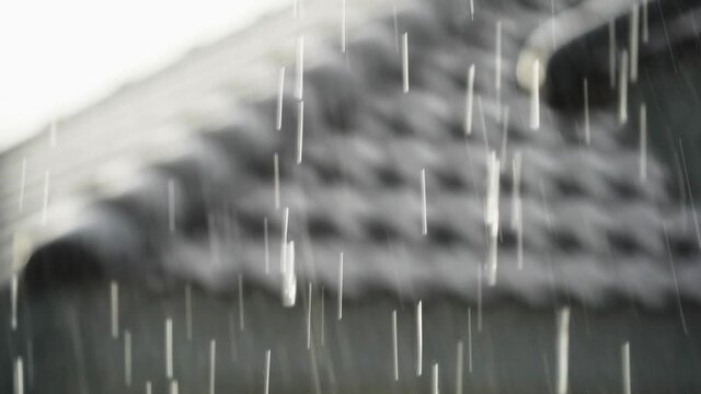 raining in streams and water droplets with a blurred roof image as a background