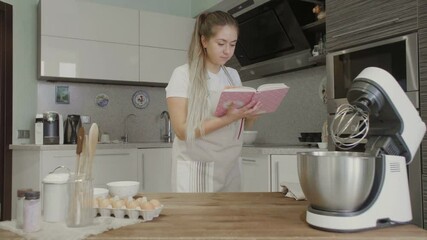 A girl in the kitchen is looking for recipes in a recipe book or in a notebook