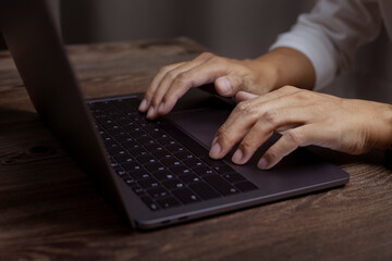 Man typing on laptop or computer concept, Closeup photo of male hands with laptop, businessman working at home office.