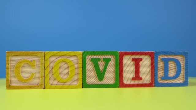 Wooden block of alphabet COVID rotating on surface