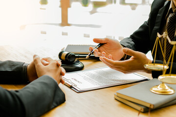 Lawyers discuss business contract documents sitting at a desk in the office of conceptual legal...