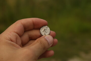 Silver coin of ancient Rome in hand