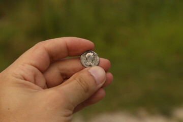 Silver coin of ancient Rome in hand