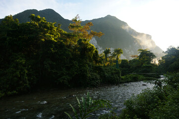 Early morning mist at sunrise over the Melinau River with Mount Benarat, Mulu, Sarawak, Borneo - obrazy, fototapety, plakaty