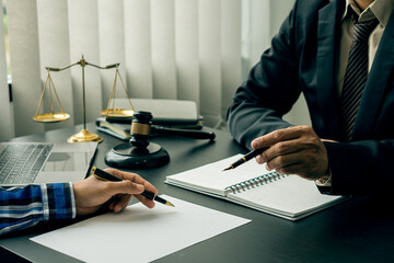 Lawyers discuss business contract documents sitting at a desk in the office of conceptual legal...