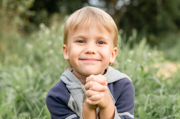 portrait of a cute little four year old smiling happy candid european kid boy in nature in the...