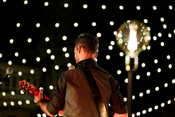 Musician on the stage, rear view, stage decorated with light bulbs