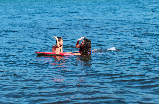 Boy and girl giving high five on a surfboard - Powered by Adobe
