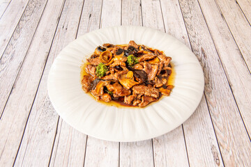 Veal recipe with vegetables and mushrooms with sauce from other Chinese recipe on white plate