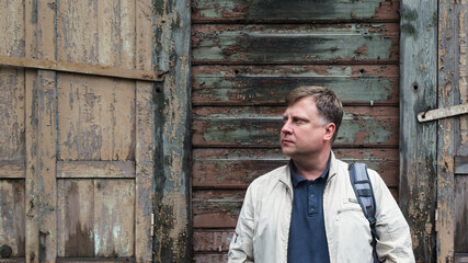Obraz premium Country man farmer stands near empty abandoned wooden building.