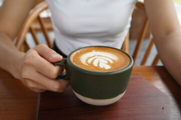 A woman drinking hot cappuccino coffee