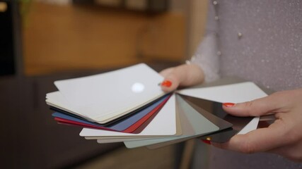 Close-up color palette for furniture in female Caucasian hands. Unrecognizable young wealthy confident woman choosing new furnishings in shop store indoors. Slow motion