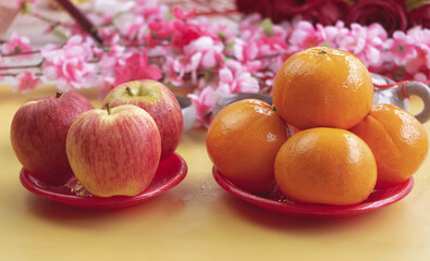 Apples plenty of waterdrops around and Oranges put inred dish,on background,