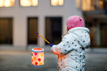 Little kid girl holding selfmade lanterns with candle for St. Martin procession. Healthy cute toddler child happy about children and family parade in kindergarten. German tradition Martinsumzug © Irina Schmidt