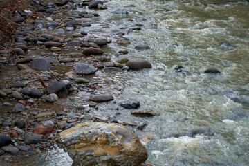 Rocky bank of a mountain river flowing down from the mountains and flowing through the city