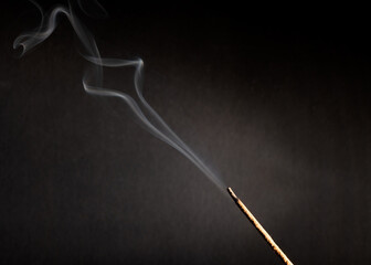 incense stick with smoke against black background 