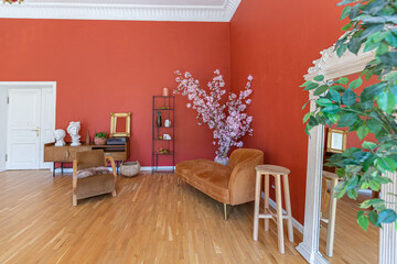 antique vintage interior in 19th century style living room with bright red walls, wood floor and direct sunlight inside the room.