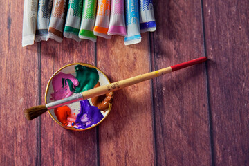 Tempera paints on the wooden table in a workshop, selective focus, Set of watercolor paints, and a...