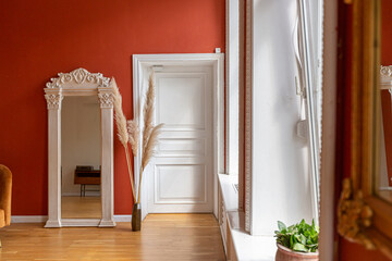 antique vintage interior in 19th century style living room with bright red walls, wood floor and direct sunlight inside the room.
