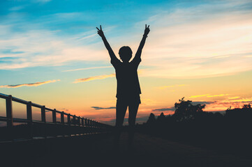 Fototapeta premium Happy celebrating winning success woman at sunset or sunrise standing elated with arms raised up.