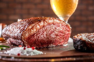 Grilled sliced cap rump steak on wooden cutting board with a glass of beer  (Brazilian picanha).