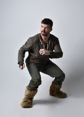 Full length  portrait of  young handsome man  wearing  medieval Celtic adventurer costume.  Standing pose, low angle perspective,  isolated on studio background.