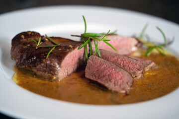 fresh cooking at home and ready to eat, delicious medium roasted game meat from the young roe deer in wine mustard sauce on a withe plate